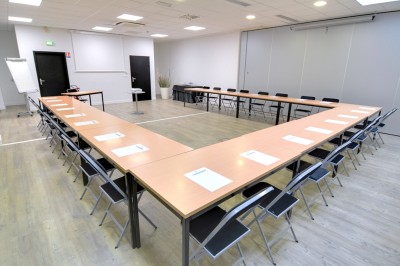 Serviettes blanches roulées posées sur un lit avec des oreillers et des draps blancs en arrière-plan.