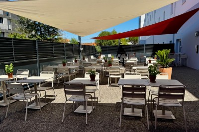 Serviettes blanches roulées posées sur un lit avec des oreillers et des draps blancs en arrière-plan.