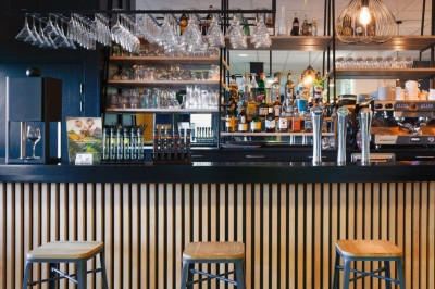 Serviettes blanches roulées posées sur un lit avec des oreillers et des draps blancs en arrière-plan.