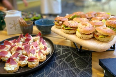 Serviettes blanches roulées posées sur un lit avec des oreillers et des draps blancs en arrière-plan.