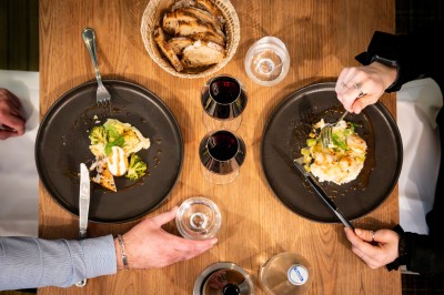 Serviettes blanches roulées posées sur un lit avec des oreillers et des draps blancs en arrière-plan.
