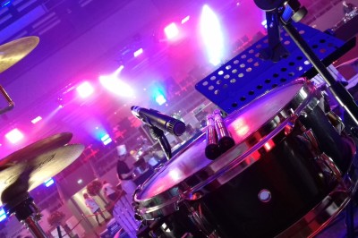 Miniature DJ Milizac (Finistère) - Florian Rion #9 Homme en chemise noire, lunettes de soleil, fumant un cigare, tenant un verre devant un bar rempli de bouteilles.