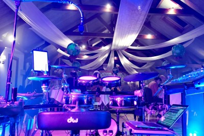 Miniature DJ Milizac (Finistère) - Florian Rion #13 Homme en chemise noire, lunettes de soleil, fumant un cigare, tenant un verre devant un bar rempli de bouteilles.