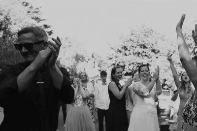 Miniature DJ Milizac (Finistère) - Florian Rion #20 Homme en chemise noire, lunettes de soleil, fumant un cigare, tenant un verre devant un bar rempli de bouteilles.