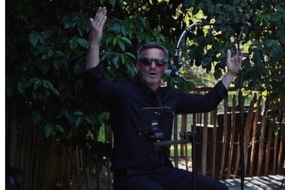 Miniature DJ Milizac (Finistère) - Florian Rion #22 Homme en chemise noire, lunettes de soleil, fumant un cigare, tenant un verre devant un bar rempli de bouteilles.