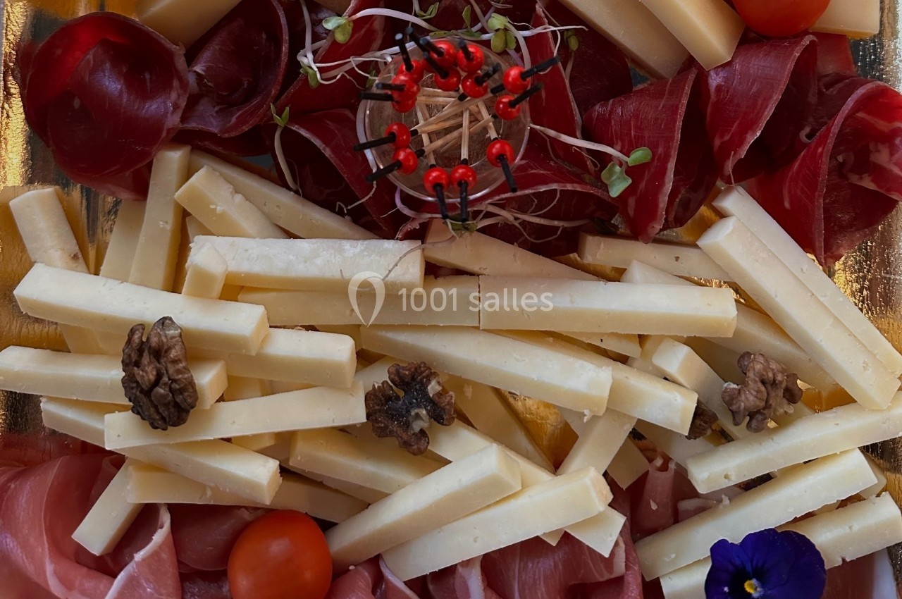 Plateau de charcuterie et fromage avec noix, tomates cerises, germes et décoration centrale en cure-dents.
