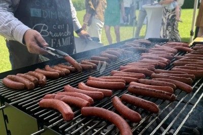 Miniature Traiteur Leers (Nord) - Tendance et Fraicheur Traiteur #18 Brochettes de viande et légumes grillant sur un barbecue en plein air, avec une fontaine et un jardin en arrière-plan.