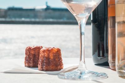 Miniature Canelés Bordelais et verre de vin en croisières sur la Garonne Une main dépose une crêpe chaude sur une assiette à l'aide d'une spatule, près d'une crêpière en extérieur.