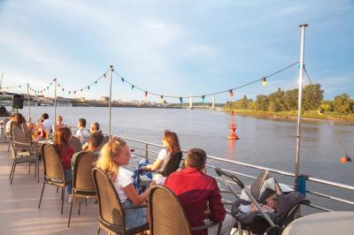 Une personne tend une assiette en carton contenant une crêpe à une autre personne, en arrière-plan flou d'une fenêtre.