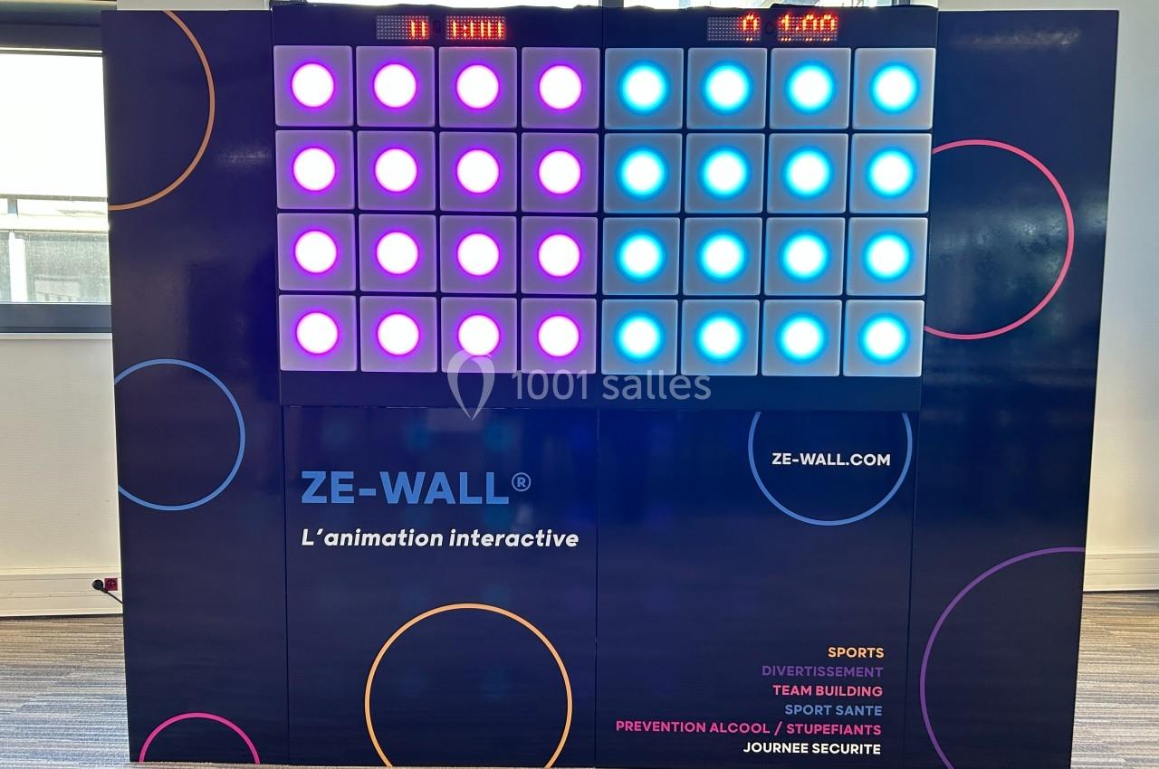 Mur interactif lumineux avec des cases colorées éclairées, utilisé pour des activités sportives et ludiques en intérieur.