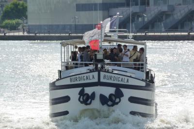 Miniature Burdigala I en navigation sur la Garonne  Bâtiment moderne en verre et métal près d'un fleuve, avec un bateau blanc amarré au premier plan.