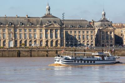 Bateau naviguant sur un fleuve devant un bâtiment historique avec une architecture classique.