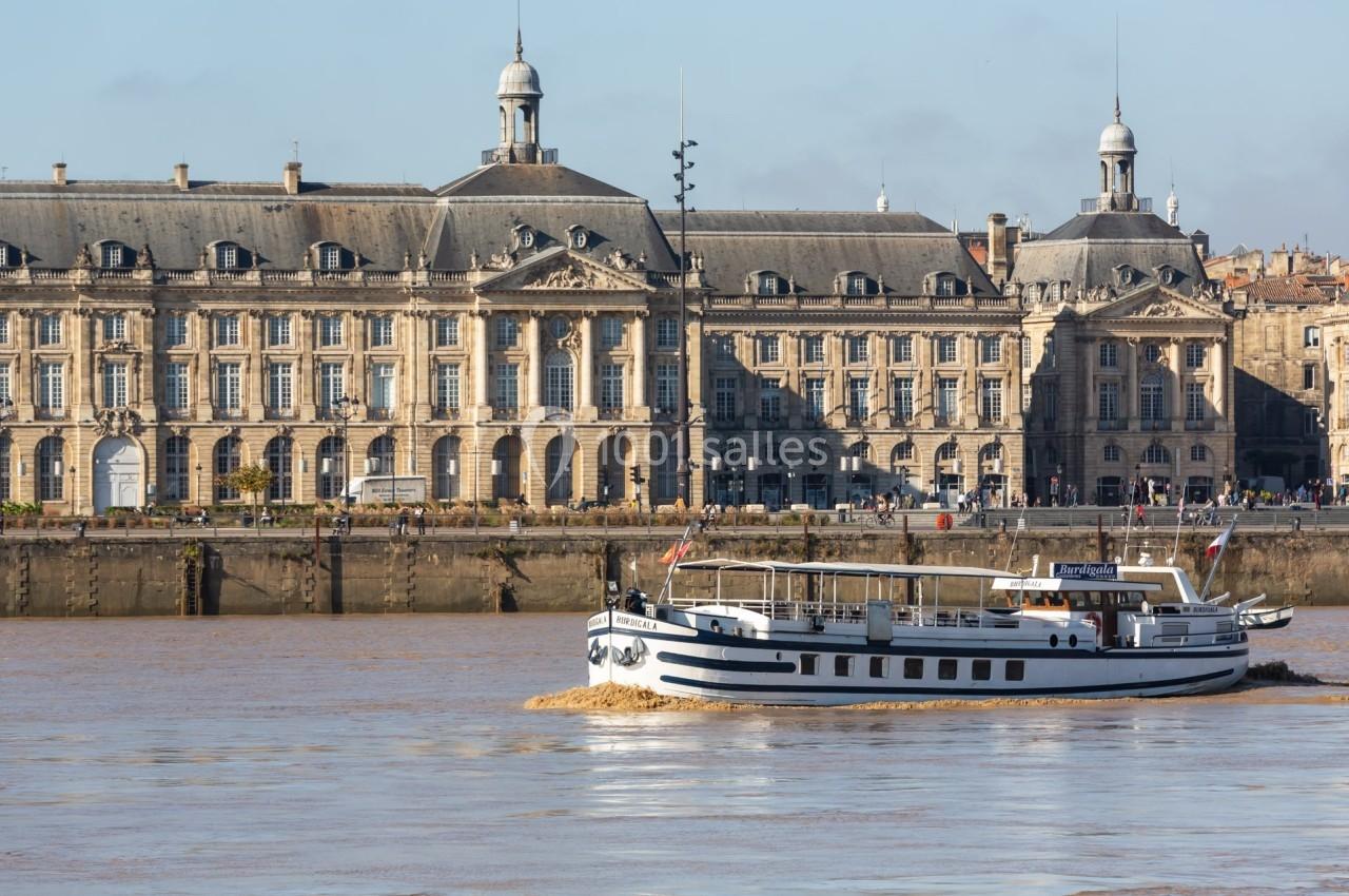 Bateau naviguant sur un fleuve devant un bâtiment historique avec une architecture classique.