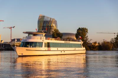 Bateau naviguant sur un fleuve devant un bâtiment historique avec une architecture classique.