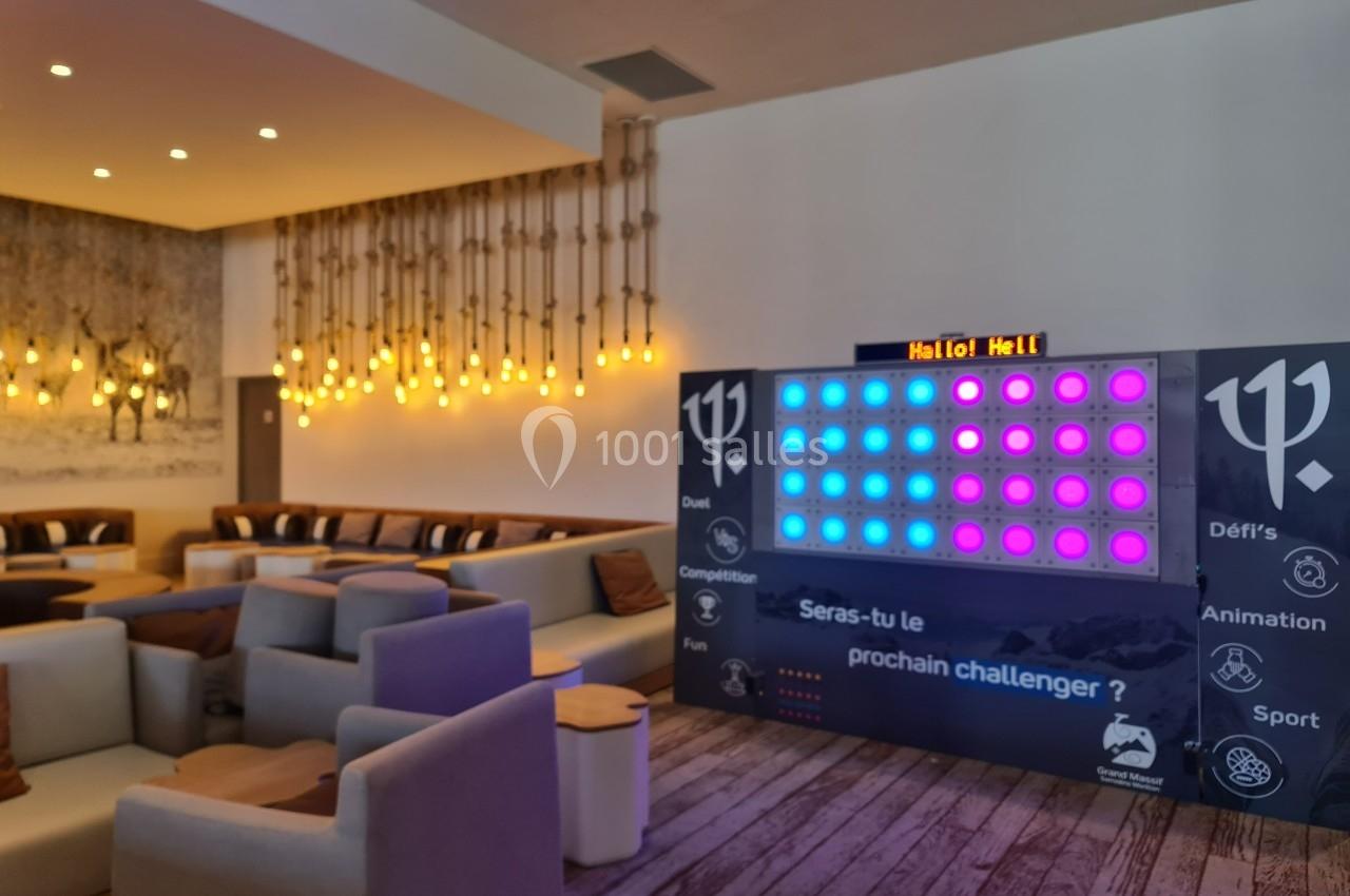 Mur interactif lumineux dans un espace lounge avec canapés, éclairage chaleureux et décor moderne en bois.