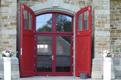 Miniature Entrée de la Salle Hermès Un couple en tenue de mariage se tient devant un officiant dans un décor festif avec sapins et guirlandes lumineuses.