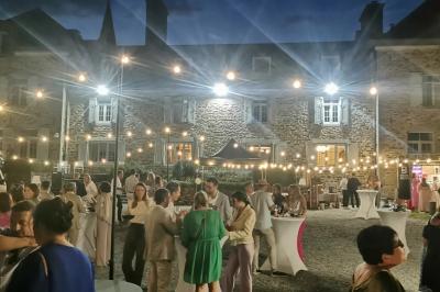 Miniature Soirée guinguette dans les jardins du château Un couple en tenue de mariage se tient devant un officiant dans un décor festif avec sapins et guirlandes lumineuses.