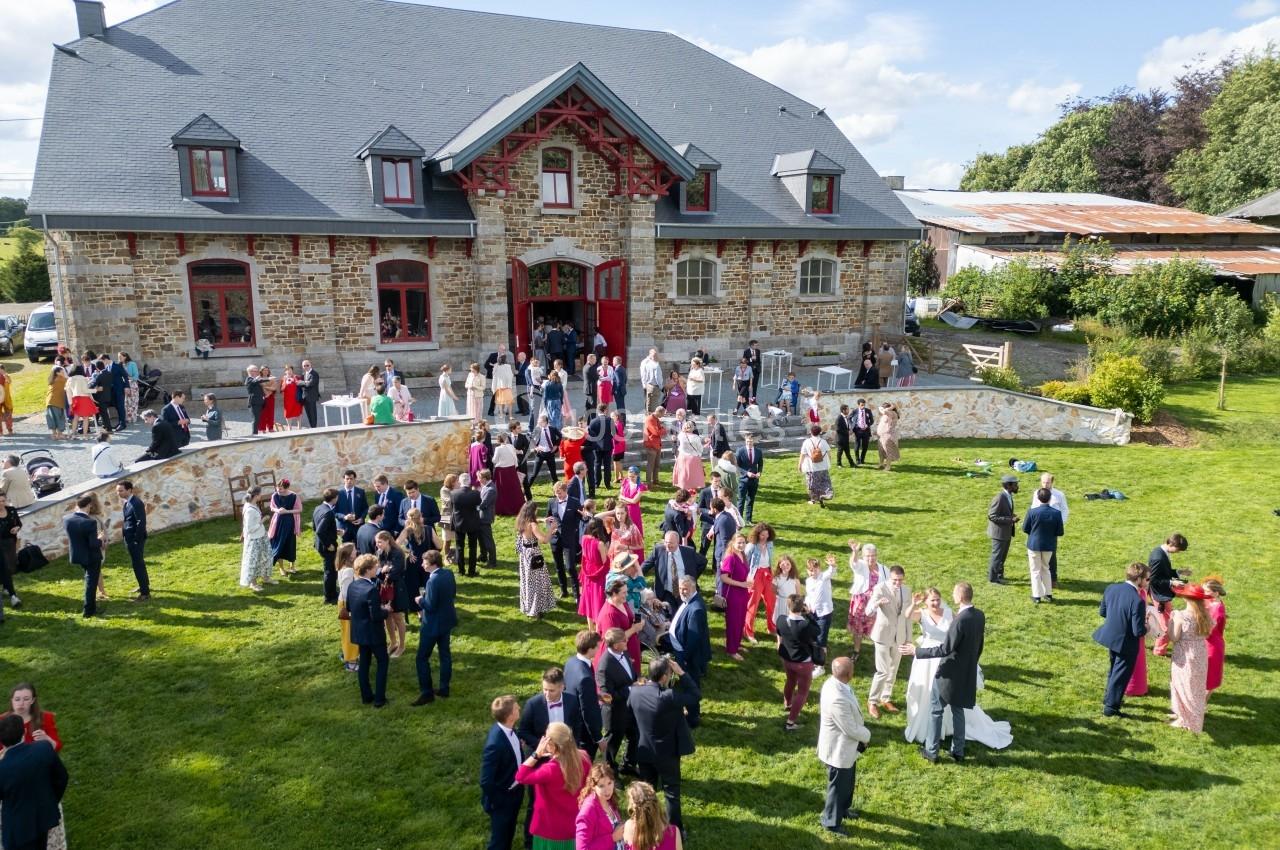 Groupe de personnes rassemblées dans un jardin devant un grand bâtiment en pierre lors d'un événement festif.