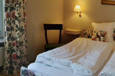 Porte d'entrée rouge à double battant ouverte, entourée d'un mur en pierre, avec des pots de fleurs de chaque côté.