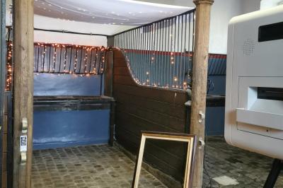 Porte d'entrée rouge à double battant ouverte, entourée d'un mur en pierre, avec des pots de fleurs de chaque côté.