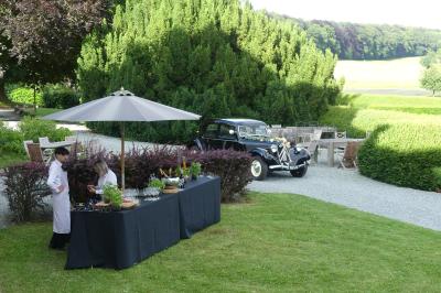 Porte d'entrée rouge à double battant ouverte, entourée d'un mur en pierre, avec des pots de fleurs de chaque côté.