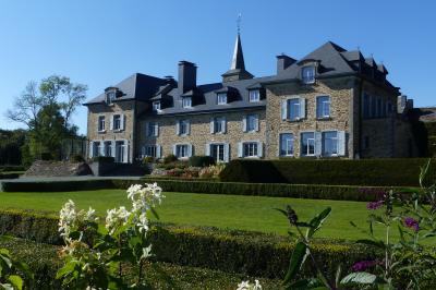 Porte d'entrée rouge à double battant ouverte, entourée d'un mur en pierre, avec des pots de fleurs de chaque côté.