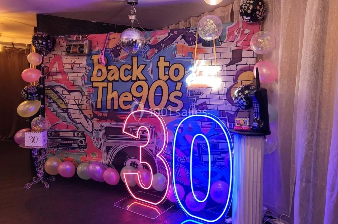 Décor festif sur le thème des années 90 avec graffitis, ballons, néons ’30’ et accessoires rétro.