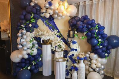 Miniature Silvie Wedding & Events #12 Figurines de mariés sur un gâteau décoré de fleurs bleues, d'une feuille argentée et d'un cœur en arrière-plan.