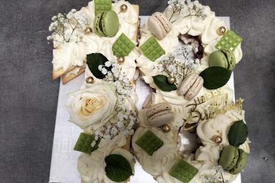 Miniature Silvie Wedding & Events #15 Figurines de mariés sur un gâteau décoré de fleurs bleues, d'une feuille argentée et d'un cœur en arrière-plan.