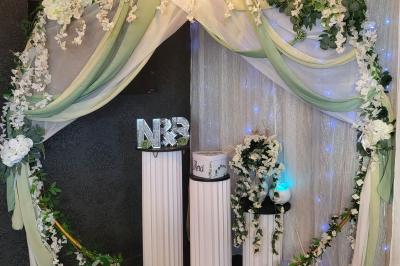 Miniature Silvie Wedding & Events #32 Figurines de mariés sur un gâteau décoré de fleurs bleues, d'une feuille argentée et d'un cœur en arrière-plan.