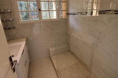 Salle de bain moderne avec lavabo, miroir éclairé, meuble de rangement et douche à paroi vitrée.
