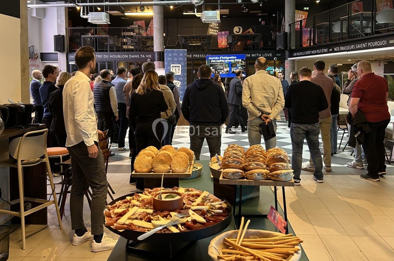 Groupe de personnes debout dans un espace intérieur, avec un buffet de nourriture en premier plan.