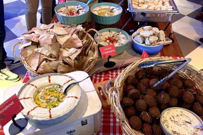 Lavabo moderne avec miroir, distributeur de savon mural et carrelage beige dans une salle de bain.