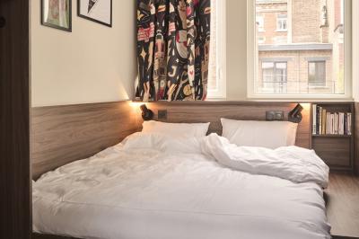 Lavabo moderne avec miroir, distributeur de savon mural et carrelage beige dans une salle de bain.
