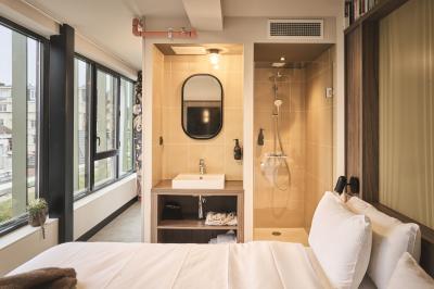 Lavabo moderne avec miroir, distributeur de savon mural et carrelage beige dans une salle de bain.