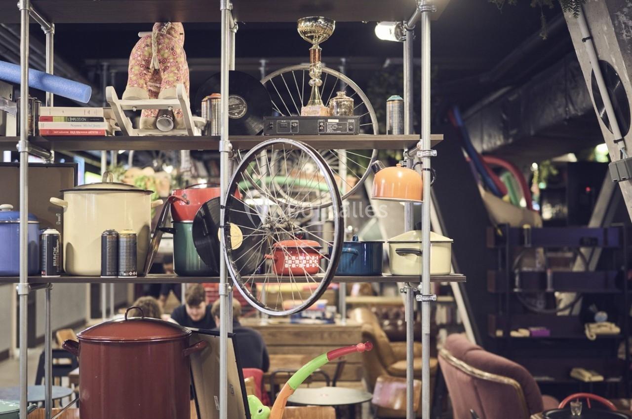 Étagère métallique contenant divers objets hétéroclites, dont des casseroles, une roue de vélo et des livres, dans un espace…