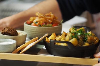 Lavabo moderne avec miroir, distributeur de savon mural et carrelage beige dans une salle de bain.