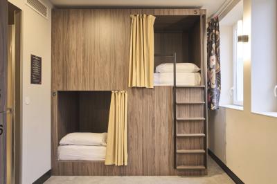 Miniature Location salle Lille (Nord) - Jost #41 Lits superposés en bois avec rideaux jaunes dans une chambre lumineuse, échelle et fenêtres sur le côté.