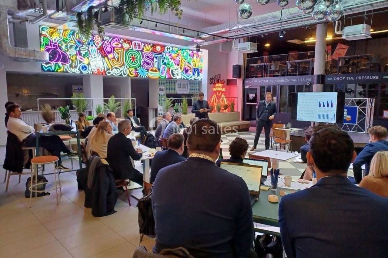 Un groupe de personnes assiste à une présentation dans un espace moderne avec des décorations colorées et des écrans.