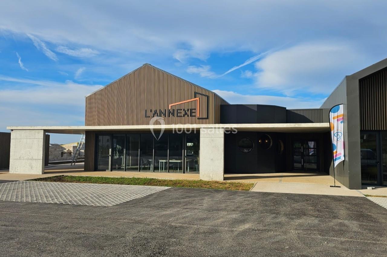 Bâtiment moderne avec façade en bois et béton, grandes baies vitrées et une enseigne visible sous un ciel dégagé.