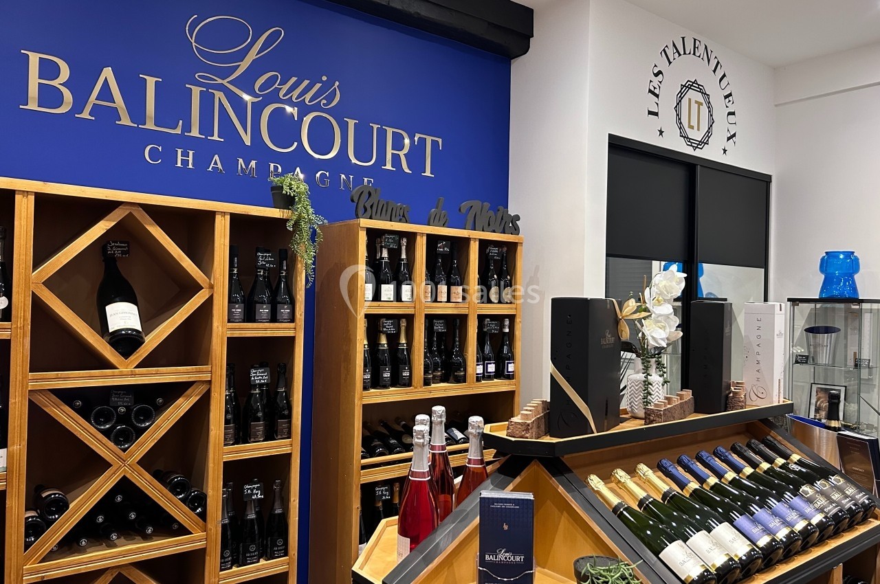 Rayonnages de bouteilles de champagne et vins dans une boutique avec une enseigne ’Louis Balincourt’.