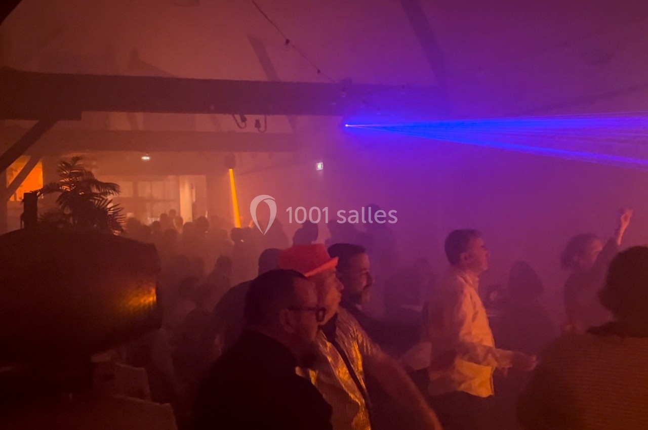 Personnes dansant dans une salle sombre avec des lumières colorées et des faisceaux laser.
