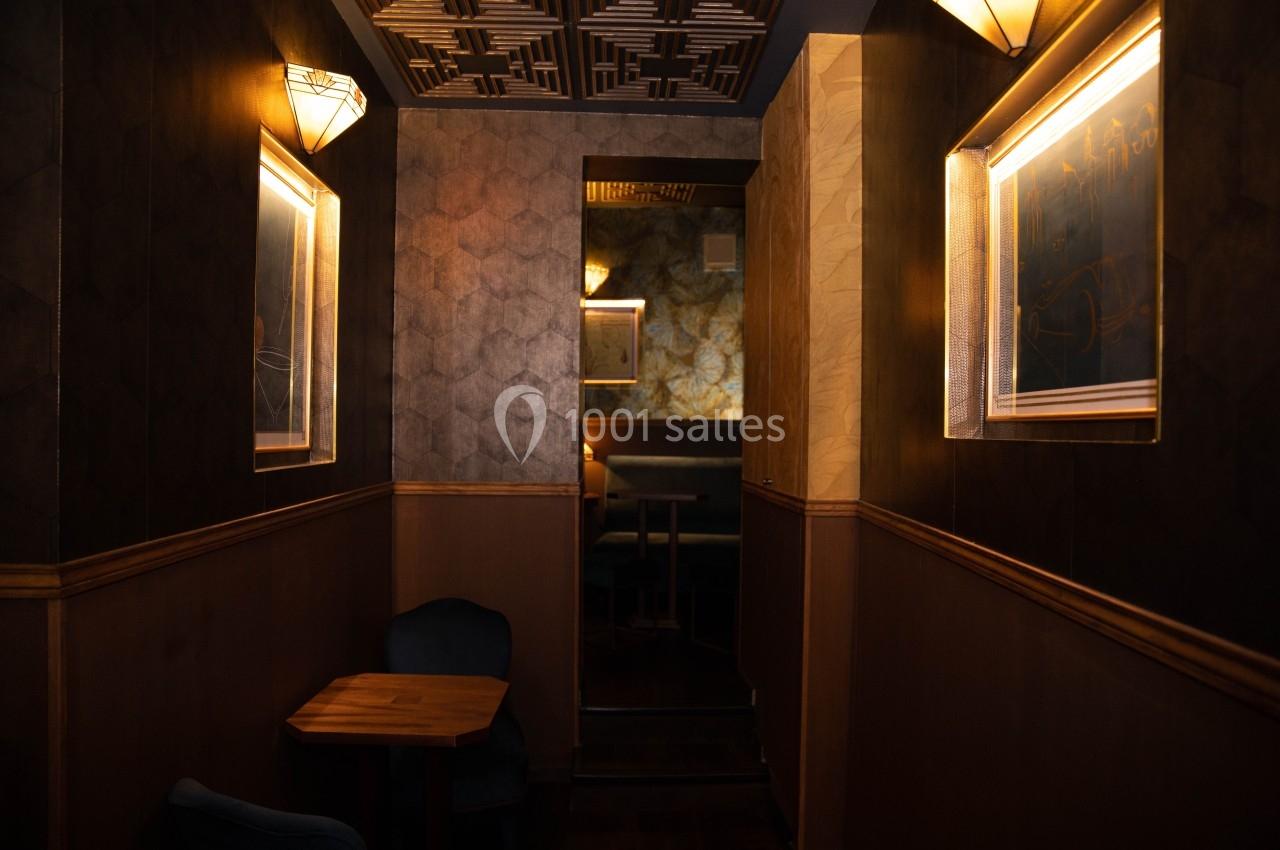 Intérieur d'un couloir sombre avec des murs texturés, éclairage tamisé et mobilier en bois et tissu.
