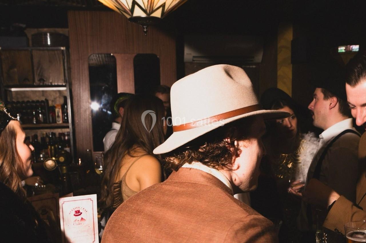 Personnes en tenue élégante discutant dans un bar à l'ambiance tamisée.