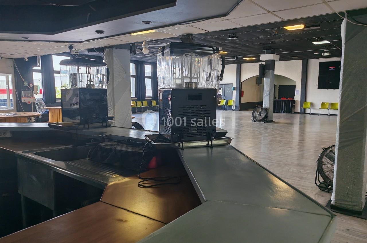 Deux blenders posés sur un comptoir dans une grande salle vide avec des chaises alignées en arrière-plan.