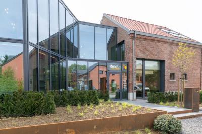 Bâtiment moderne avec façade en verre et briques, entouré de végétation et d'une allée pavée.