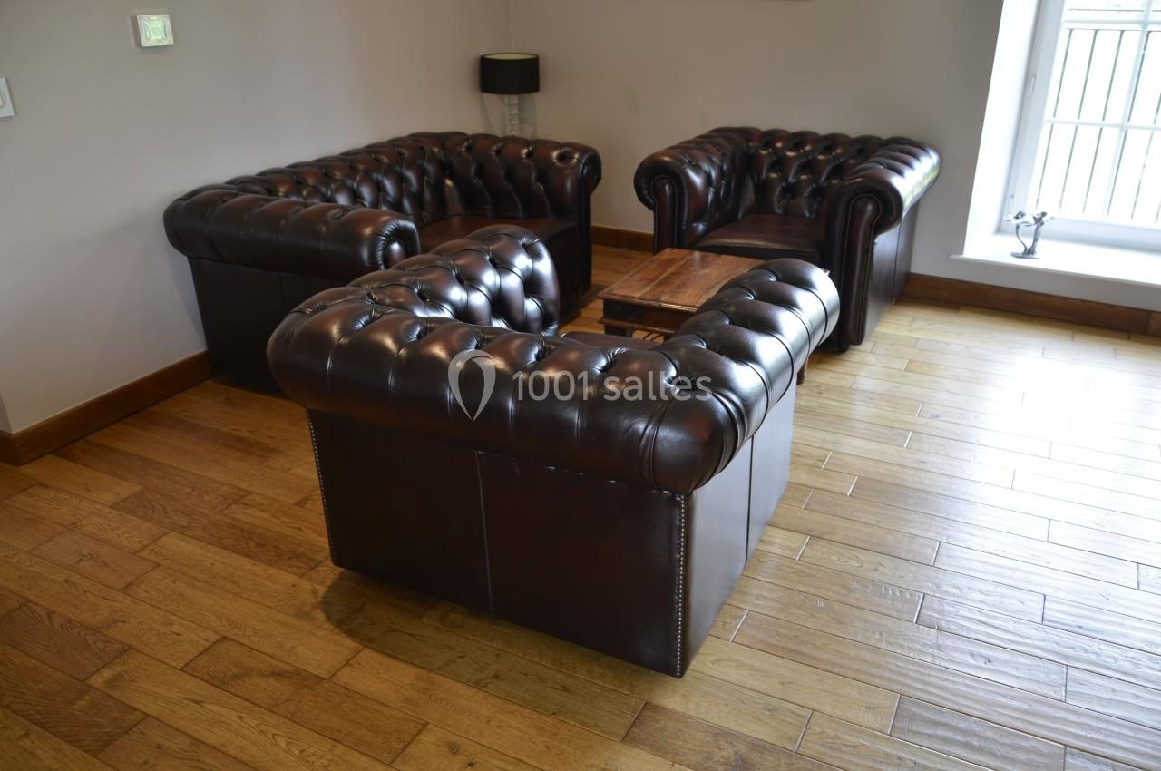 Canapés en cuir marron disposés en U autour d'une table basse en bois, sur un sol en parquet clair.