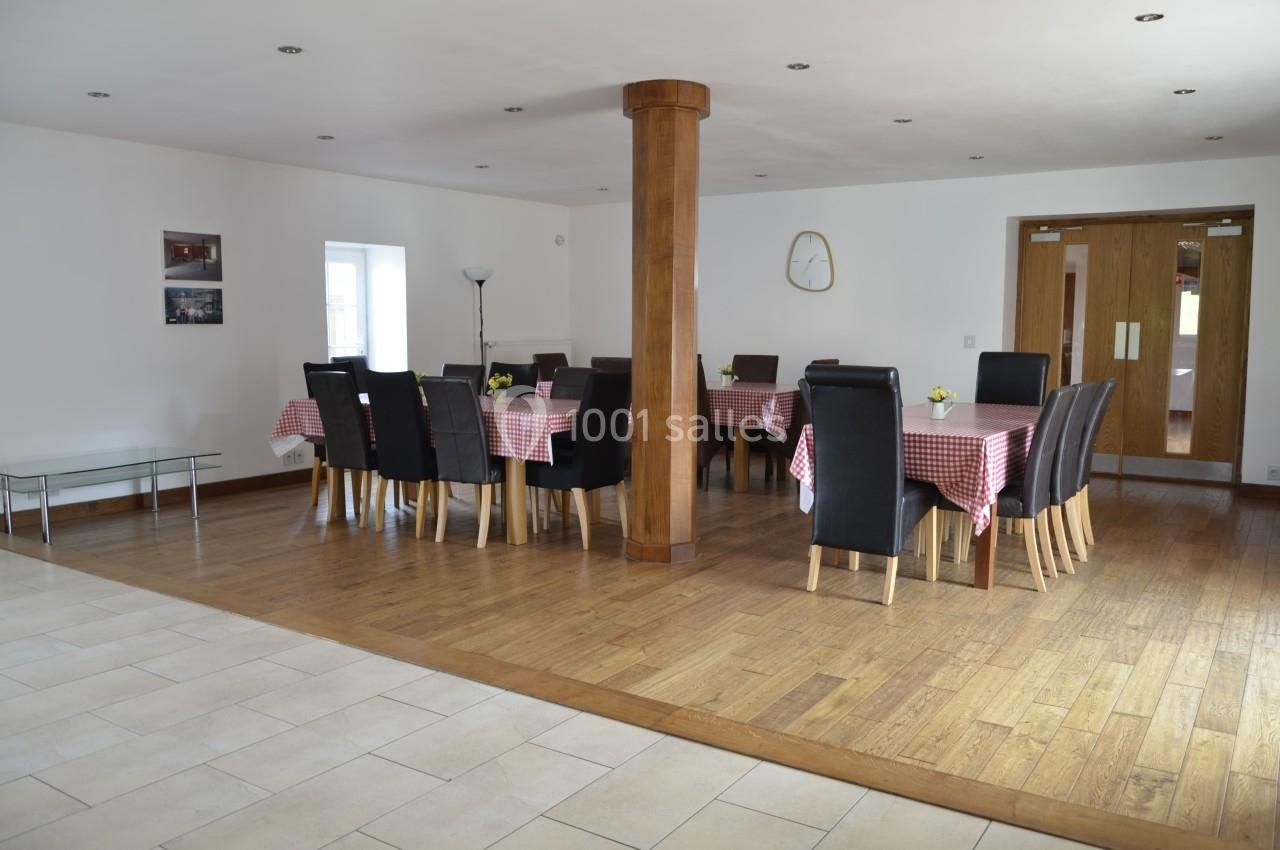 Salle à manger lumineuse avec tables recouvertes de nappes rouges à carreaux, chaises noires et sol en bois.