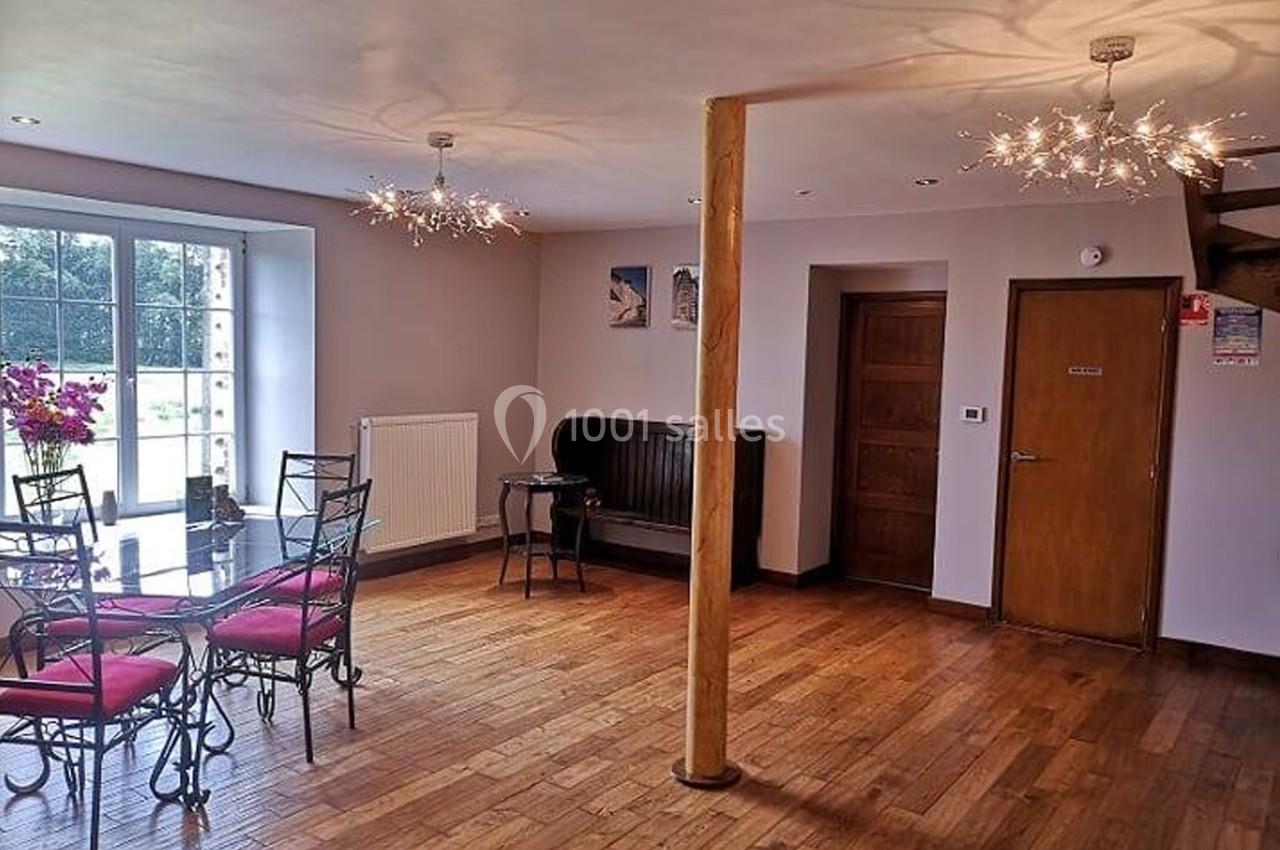 Salle lumineuse avec parquet en bois, table et chaises en métal, décorations murales et grandes fenêtres donnant sur l…