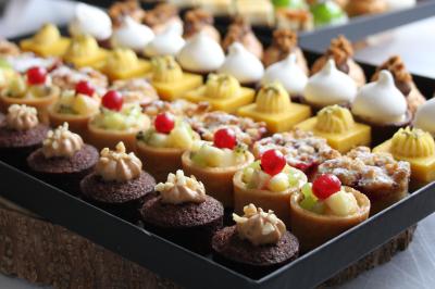 Miniature Traiteur Magny-les-Hameaux (Yvelines) - Lars Traiteur #8 Gâteau de fête décoré de bougies scintillantes, entouré de desserts et de convives en arrière-plan flou.